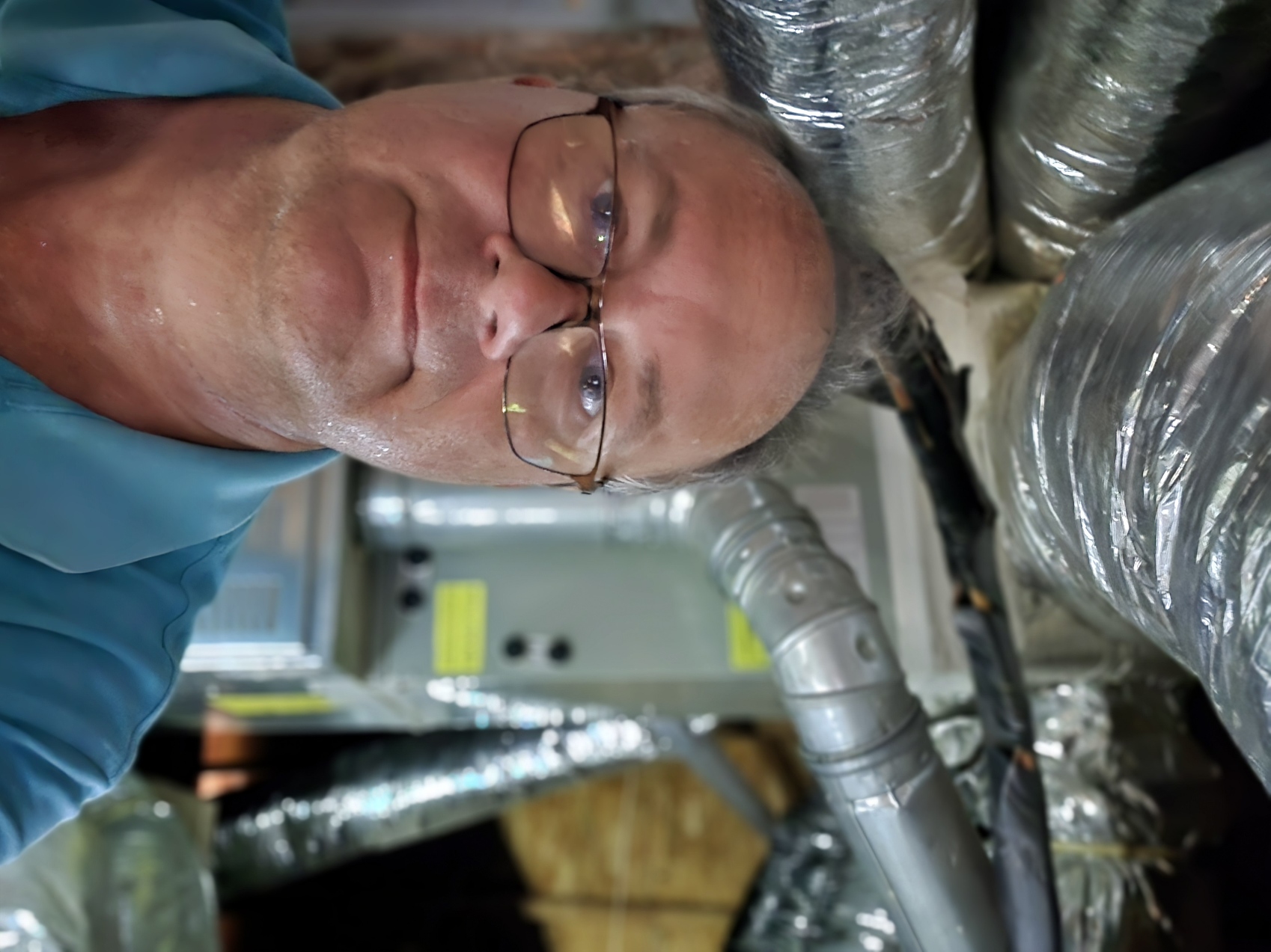Technician sweating in attic to get the a/c cooling again. Air conditioner repair McDonough